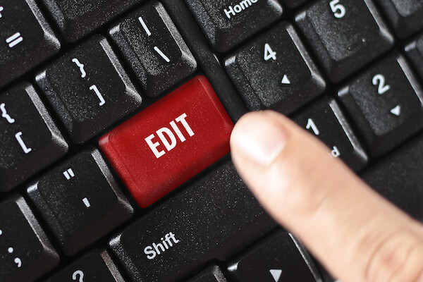 close up of a person holding a light bulb that is glowing and writing in a notebook.