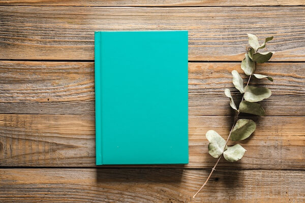 close up of a person holding a light bulb that is glowing and writing in a notebook.