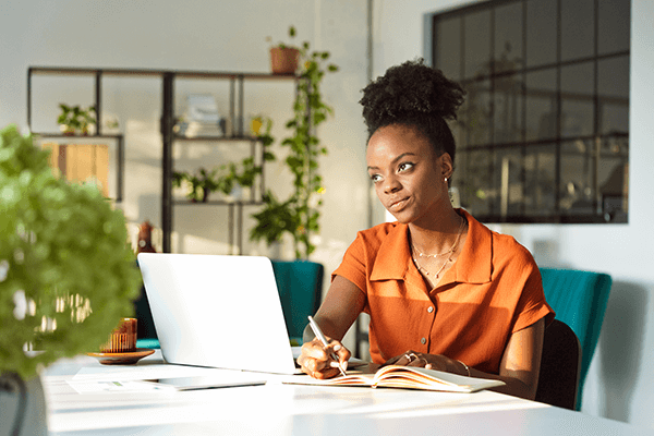 Crafting a Winning Marketing Plan- Publisher's Edition A woman wearing an orange blouse working in an office looking off to the side in deep thought.