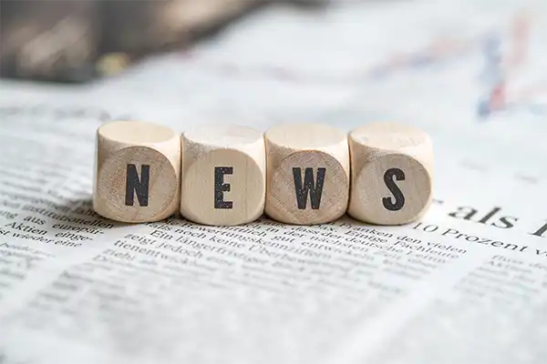 9 Ways to Find Inspiration from News Headlines and Current Events The word "NEWS" spelled out in small wooden blocks. The blocks are resting on newspaper